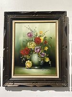 Frontal view of oil painting showing floral bouquet in carved dark wood frame with gold inner trim.