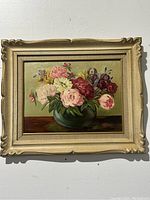 Frontal view of the framed oil painting showing flowers in a green vase on a brown table.