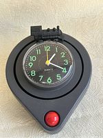 Front view of clock face showing black dial with glow-in-the-dark green numbers and train locomotive figure mounted on top.