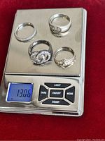 Four vintage style sterling silver rings on a digital scale showing weight 13.06 grams.