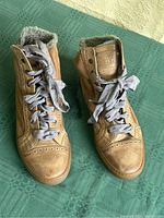 Pair of tan leather high top sneakers by Brunello Cucinelli showing upper and side details with shearling lining and satin gray laces.