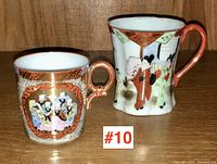Two Asian porcelain demi-tasse cups with detailed hand-painted scenes and gold accents.