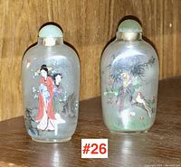 Front view of both snuff bottles side-by-side showing paintings and stoppers