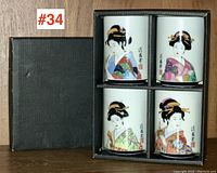 Boxed set of four Asian porcelain tea cups with geisha designs inside black box