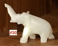 Side view of white onyx elephant figurine showing shape and trunk raised.