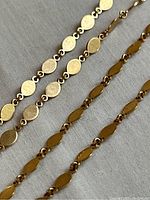 Close-up of alternating oval navette and round disc links showing polished finish