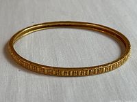 Full view of gold bangle showing patterned exterior