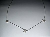 Necklace laid flat on white background showing three star-shaped diamond pendants
