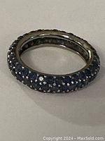 Angled view on flat surface showing three rows of blue sapphires and gold profile