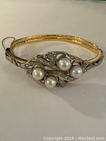 Front view showing scrolling white metal motif set with four round cultured pearls and diamond accents
