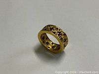 Angled view of ring on plain background showing band thickness, openwork lattice and rubies