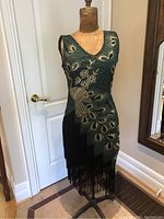 Front view on mannequin showing peacock motif, V-neckline and fringe hem.