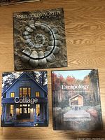 Photo of three coffee table books arranged on wooden floor, showing covers of Andy Goldsworthy, Escapology, and Cottage
