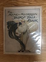 Front cover of The Anne Anderson Fairy-Tale Book showing art nouveau style printed boards depicting a robed woman with a black bird, protected in clear sleeve