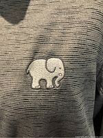 Close-up of the Ivory Ella embroidered elephant logo on the chest of the sweatshirt.