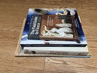 Three knitting and spinning books stacked on wooden floor: The Field Guide to Fleece, The Spinner's Book of Fleece, The Knitter's Book of Yarn.