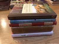 Stack of six books showing titles including 'Adventures in Yarn Farming,' 'Everybody Writes,' and a McGill book.