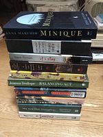 Stack of 11 paperback fiction books from various authors showing titles and spines.