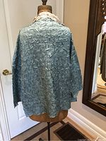 Back view of a reversible silk jacket in blue textured fabric on a dress form.