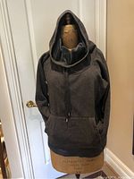 Front view of the deep blue sweater with a large hood and kangaroo pocket on dress form.