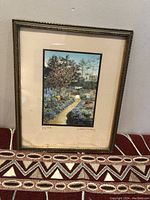 Framed colored photograph showing a garden path with flowers and trees, with visible signatures and a title on the mat board.