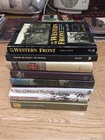 Stack of nine WW1 and military history books on a wooden surface showing spines and partial covers.