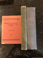 Photo showing all three WW1 books standing together: orange paperback, green cloth hardcover, and gray cloth hardcover with faded red text.