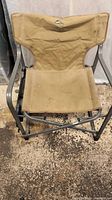 Front view of light brown camping chair showing fabric seat and metal frame