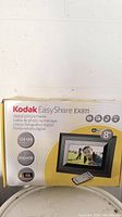 Photo of Kodak EasyShare EX811 digital picture frame box showing product features including 8 inch screen, 128 MB memory, 800x480 resolution, WiFi compatible, and remote control included.