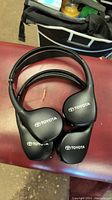 Four black wireless Bluetooth headphones with Toyota logo, laid flat on a surface.