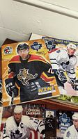 Close-up of several hockey magazines showing players in full hockey gear including helmets, gloves, and jerseys with Toronto Maple Leafs logos and a black, red, and yellow jersey from Sheffield Steelers.