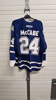 Front view of blue Toronto Maple Leafs hockey jersey with autograph on number 24, showing McCabe name.
