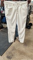 Front view of white men's golf pants showing entire pant held up by person.