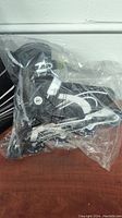 Photo of black and white size 12 roller blades in a plastic bag.