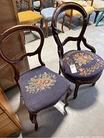 Pair of two vintage wooden chairs with floral needlepoint upholstery seats, dark wood frames, and rounded backs