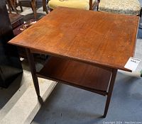 Overall view of square coffee table showing top, legs, and lower shelf