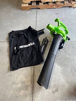Greenworks leaf blower with black collection bag, extension, and battery charger