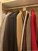 Seven ladies blazers and jackets hanging in a closet, mix of brown, red, beige colors.