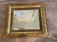 Front view of rectangular mirror with ornate gold frame showing decorative scrollwork and lattice patterns.