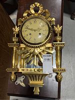 Front view of the gold-tone Westerstand pendulum wall clock showing full clock face, decorative elements, and winding key placed beside it.