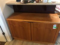 Front view of wood side cabinet showing two paneled doors and water stain marks on top.