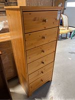Front view of slim highboy dresser showing six drawers and wooden knobs.