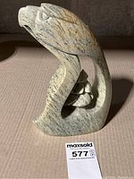 Front view of stone carved eagle with tree on a flat surface, showing detailed eagle head and part of tree.