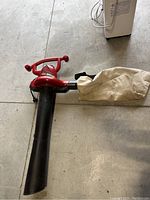 Full side view of Toro electric leaf blower vac showing red motor housing, black blower tube, and tan collection bag attached.