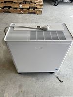 Full front view of white Vissani dehumidifier with power cable wrapped on top, showing simple design and air vents on top surface.