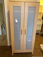 Front view of the wardrobe showing the two frosted glass panel doors with wooden handles.