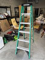 Full view of the Werner 5 step ladder showing green fiberglass frame and aluminum steps in a warehouse setting.