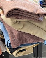 Stack of five folded wool blankets in various solid colors and patterns.
