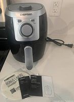 Full front view of Chefman TurboFry air fryer unit on countertop, showing timer dial, power and heating indicators, and silver handle basket.