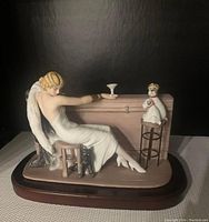 Front view of the 1932 Cocktail Louis Icart figurine on wood base showing a woman in white dress with two dogs by a bar counter.